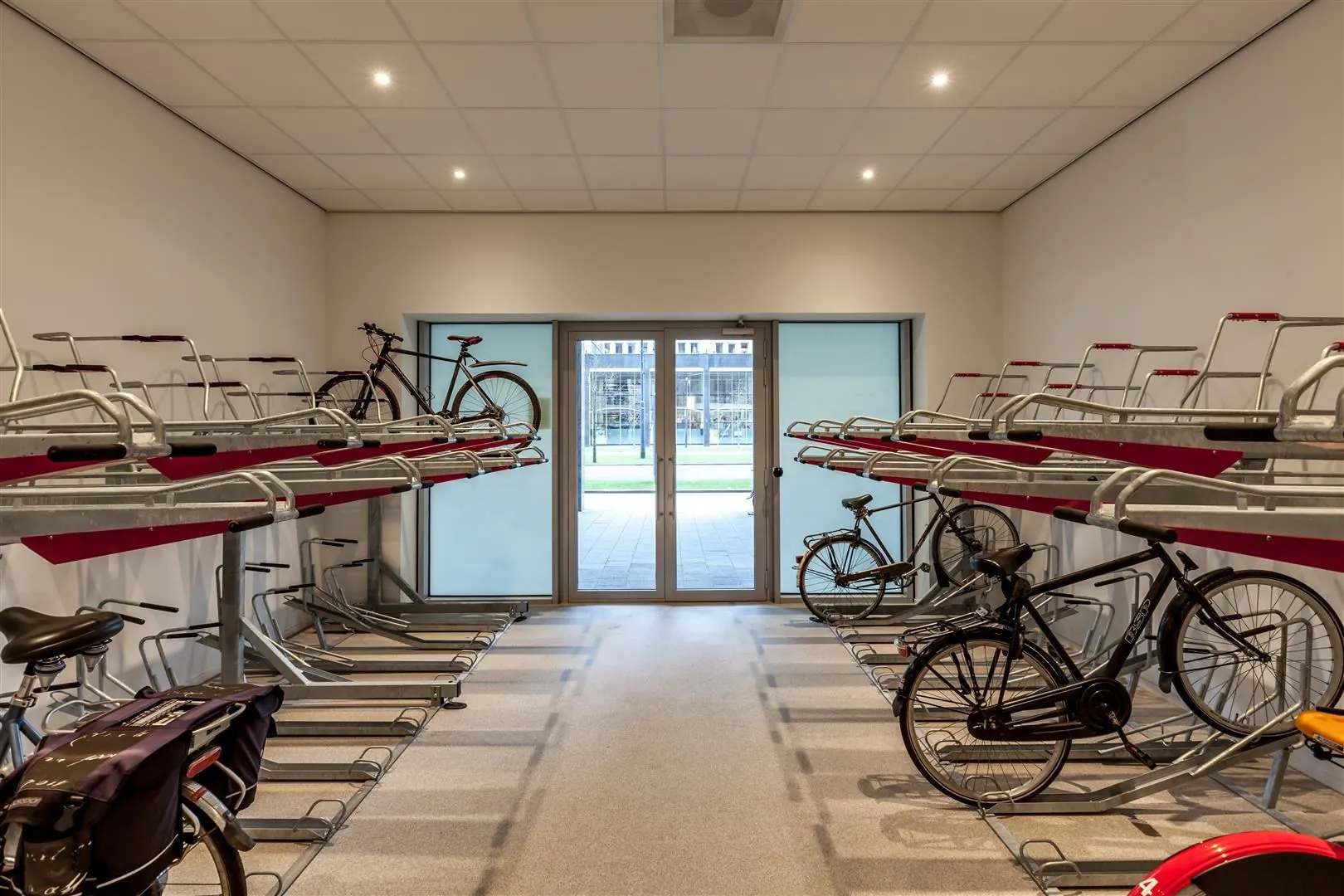 Fietsenstalling met dubbele rekken en enkele fietsen in een helder verlichte ruimte.