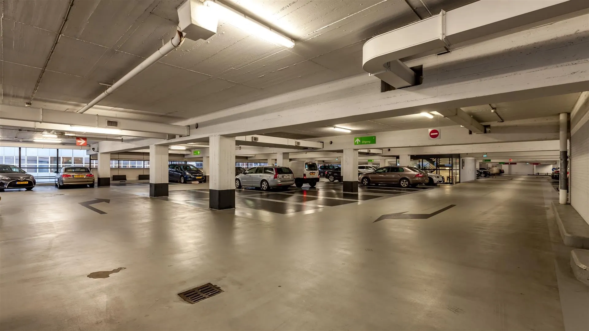 Parkeergarage met geparkeerde auto's en bewegwijzering naar de uitgang.