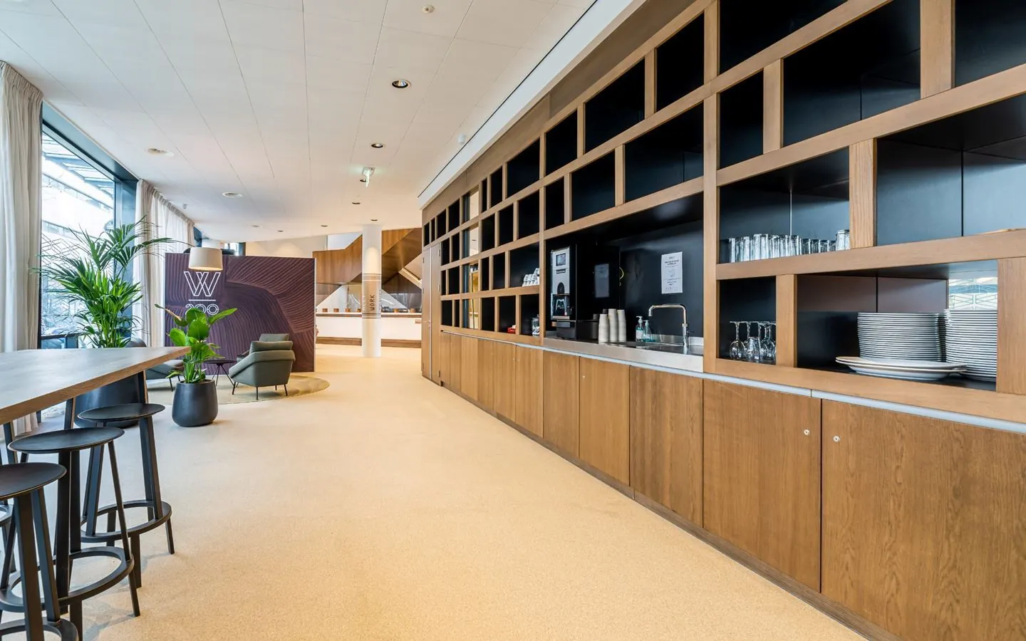 Moderne kantoorruimte met houten kasten, planten en zithoek.