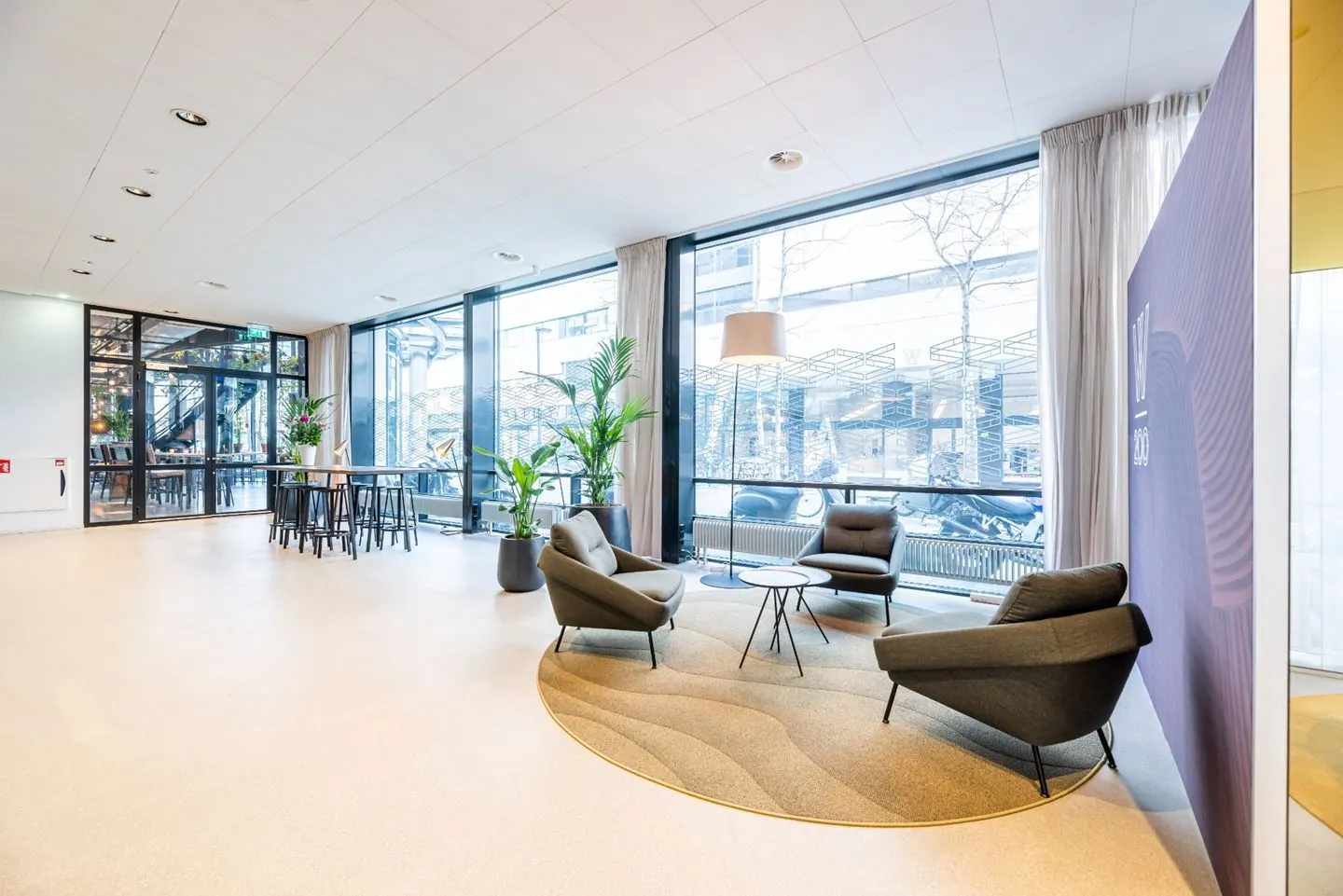 Een moderne en lichte kantoorruimte met loungestoelen en grote ramen.