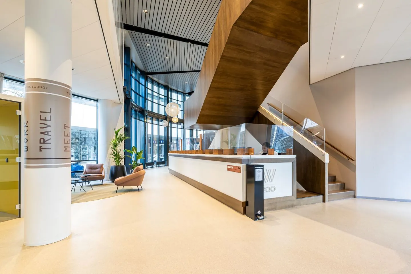Moderne hotellobby met receptiebalie, zitgedeelte en grote ramen.