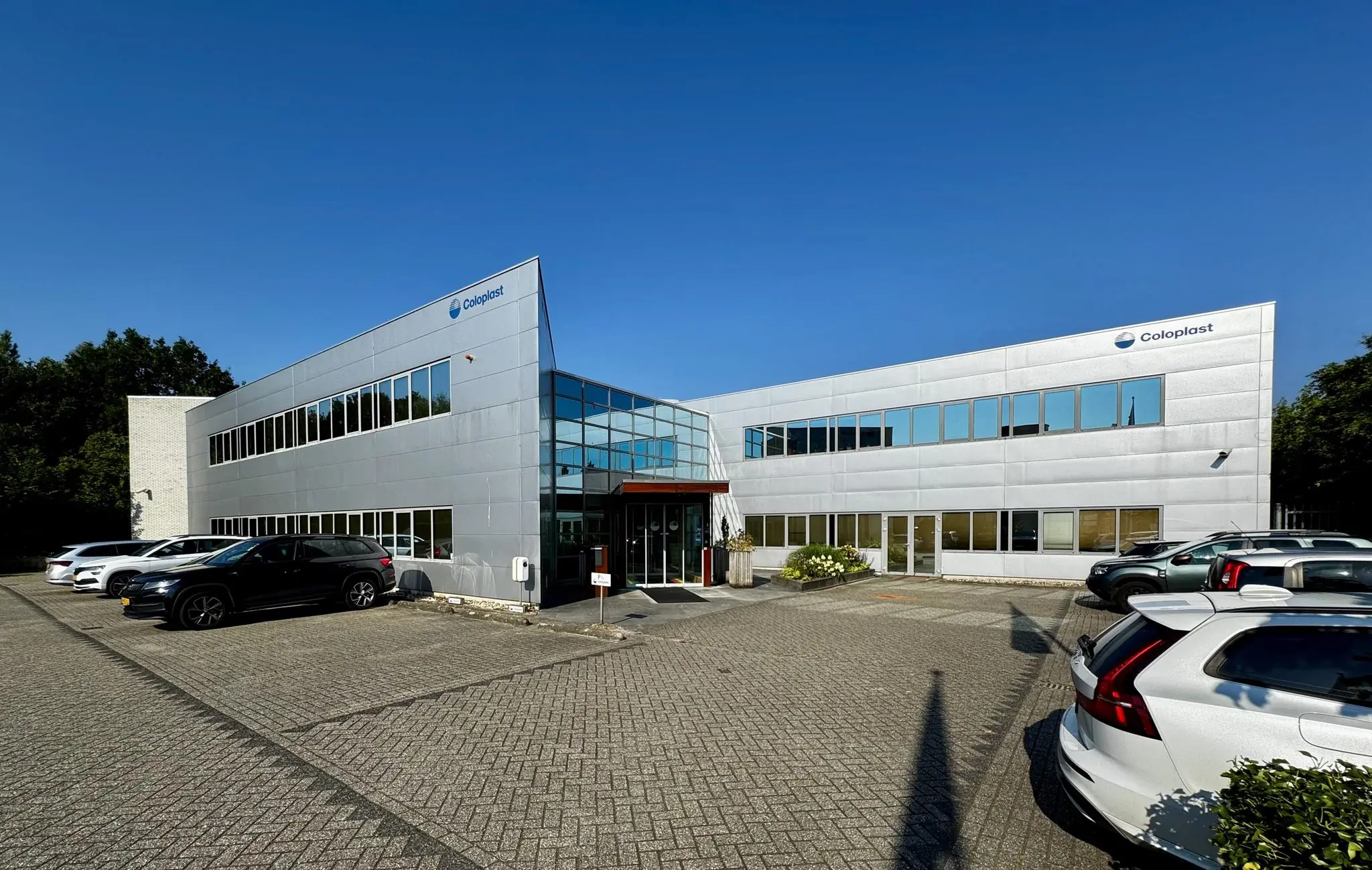 Het moderne kantoorgebouw van Coloplast aan de Softwareweg met parkeerplaatsen aan de voorzijde.