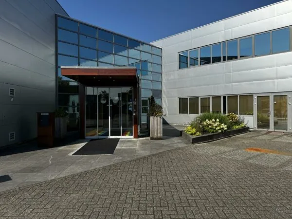 Ingang van een modern kantoorpand aan de Softwareweg met glazen gevel en bloembakken.