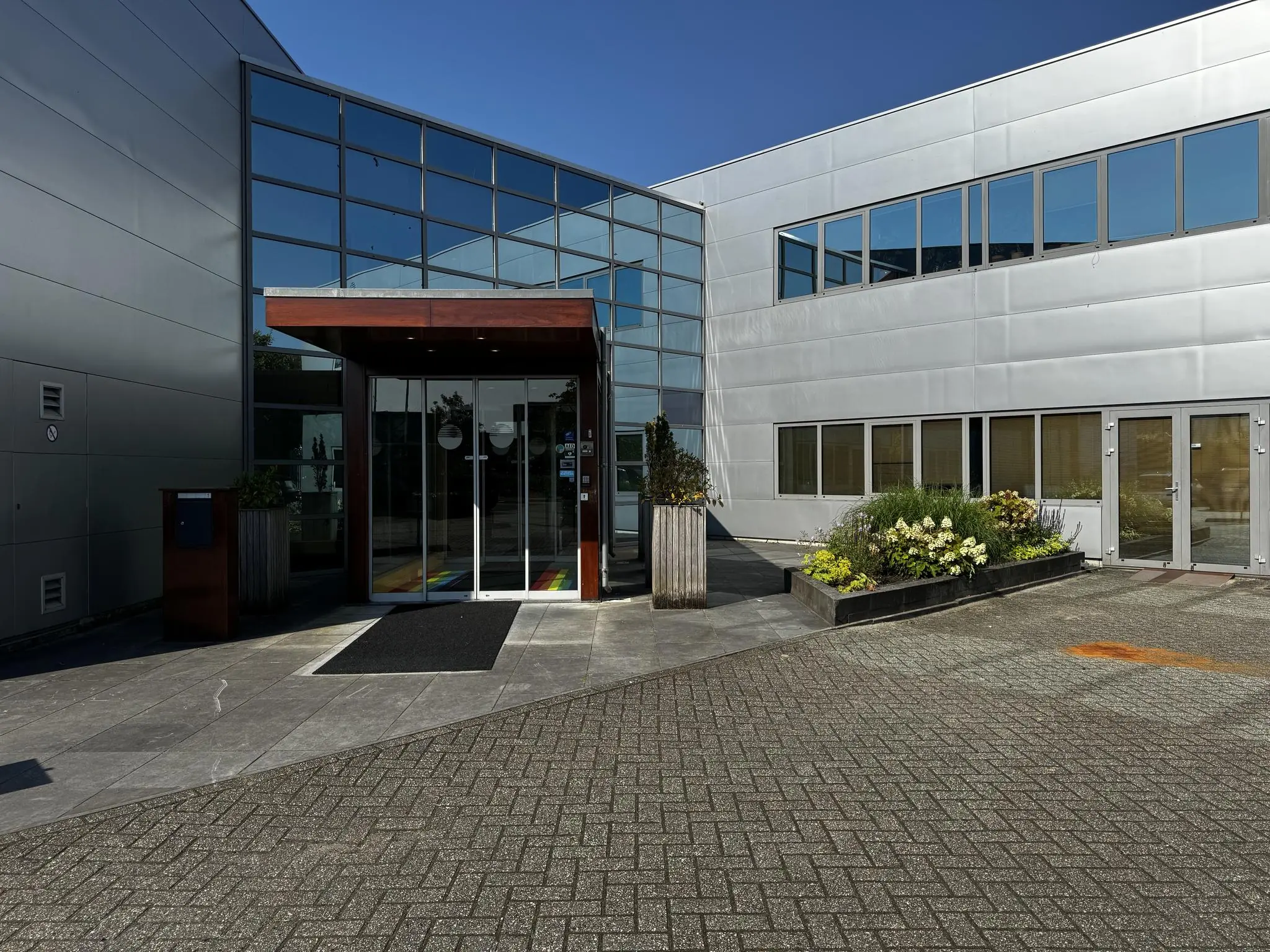 Ingang van een modern kantoorpand aan de Softwareweg met glazen gevel en bloembakken.