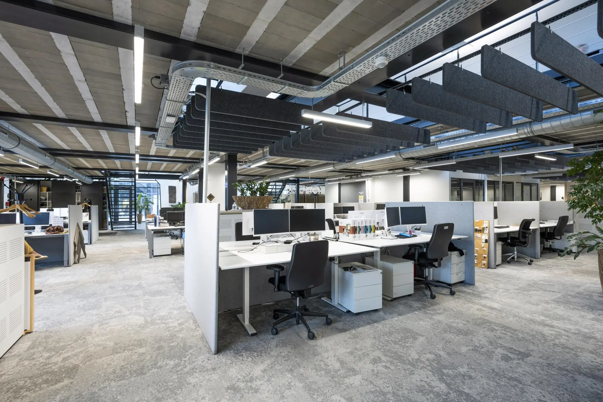 Moderne open kantoorruimte aan de Abram Dudok van Heelstraat met werkplekken, bureaustoelen en akoestische panelen aan het plafond.