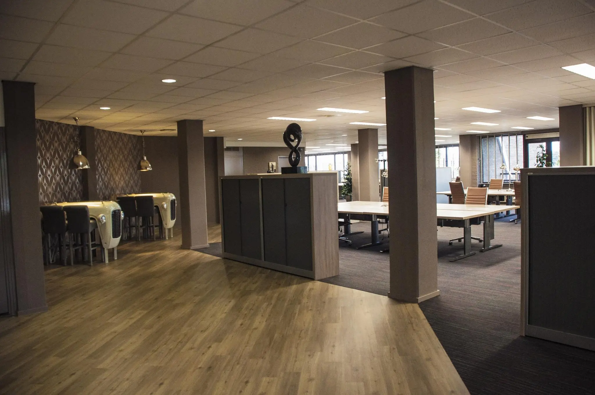 Modern kantoorinterieur aan de Zaagmolenlaan met open werkplekken, vergadertafels en unieke bureaus gemaakt van klassieke autoneuzen.