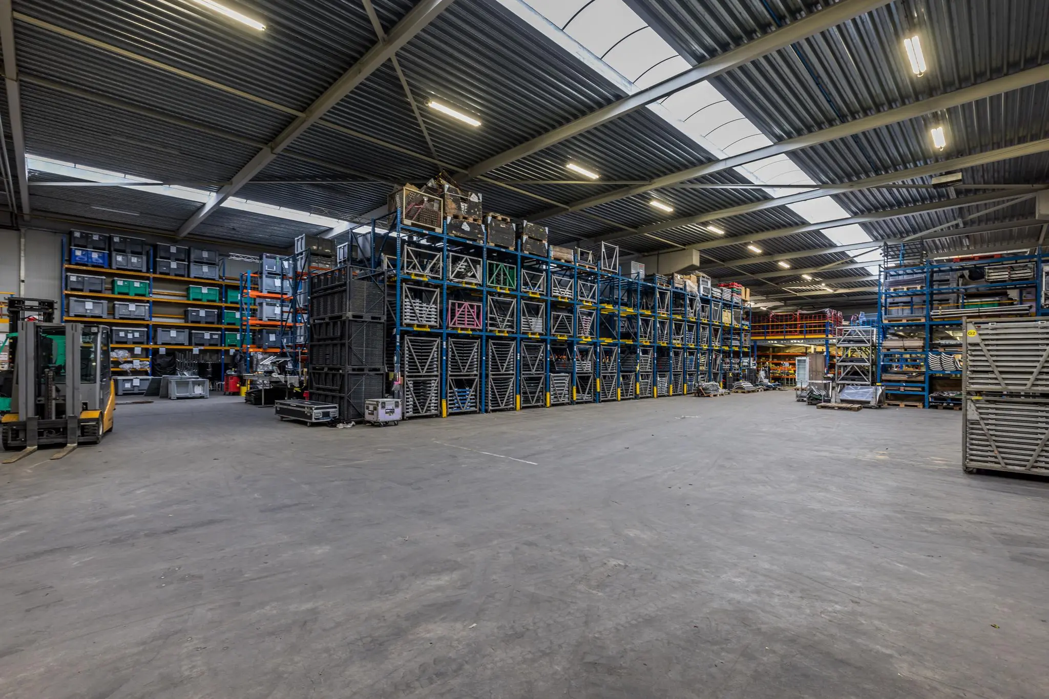 Ruim magazijn van Veldzigt met hoge stellingen vol metalen onderdelen en opslagkisten.