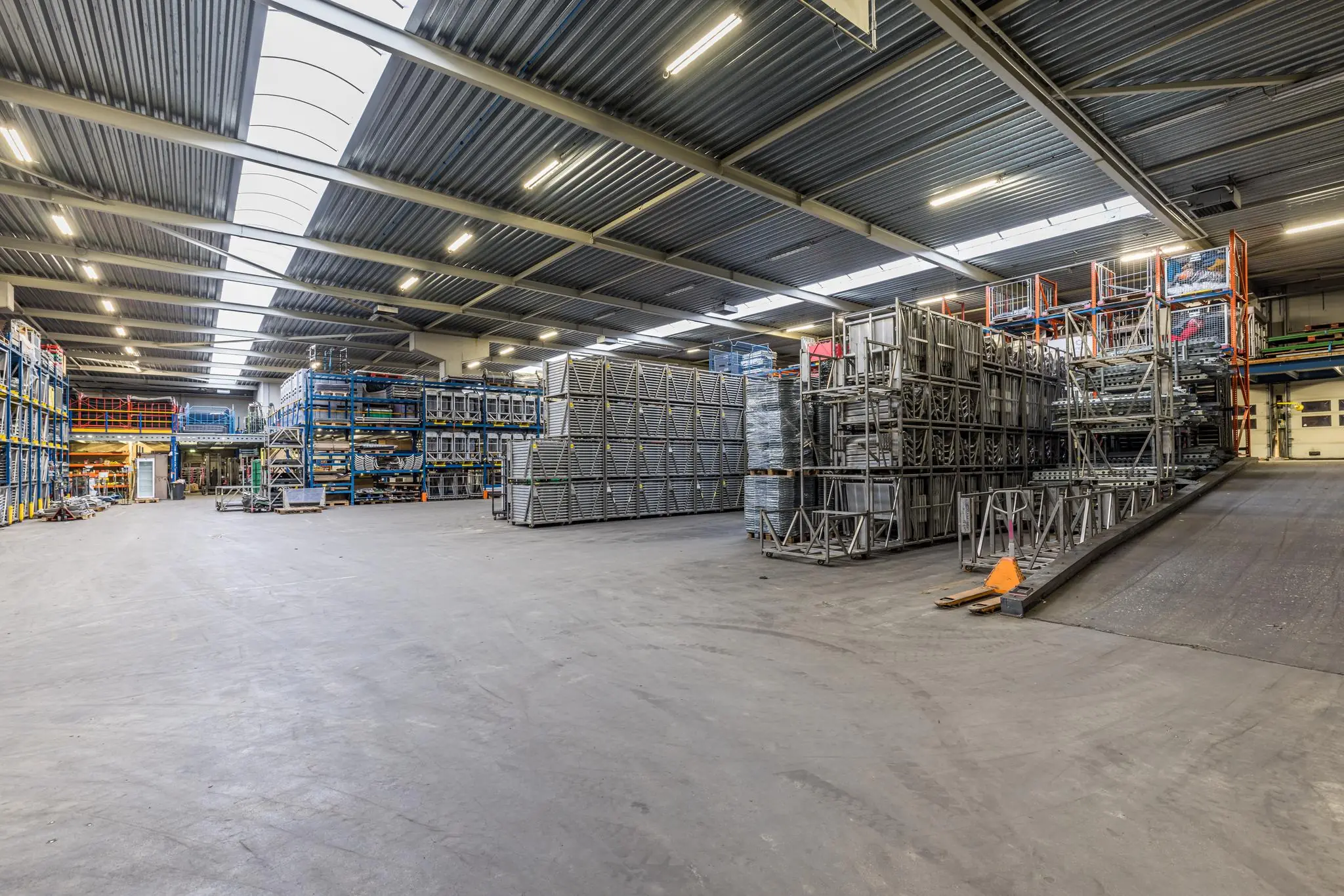 Ruime en goed verlichte opslaghal van Veldzigt met metalen stellages en opgestapelde materialen.