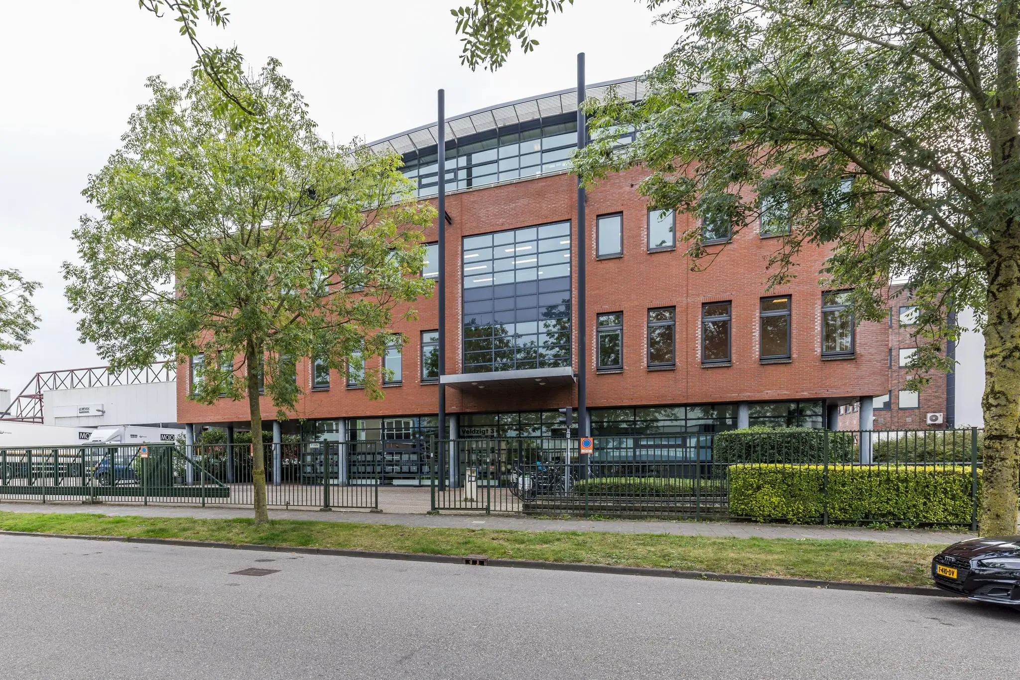 Modern kantoorgebouw aan de Veldzigt 3 met een bakstenen gevel en grote glazen raampartijen.