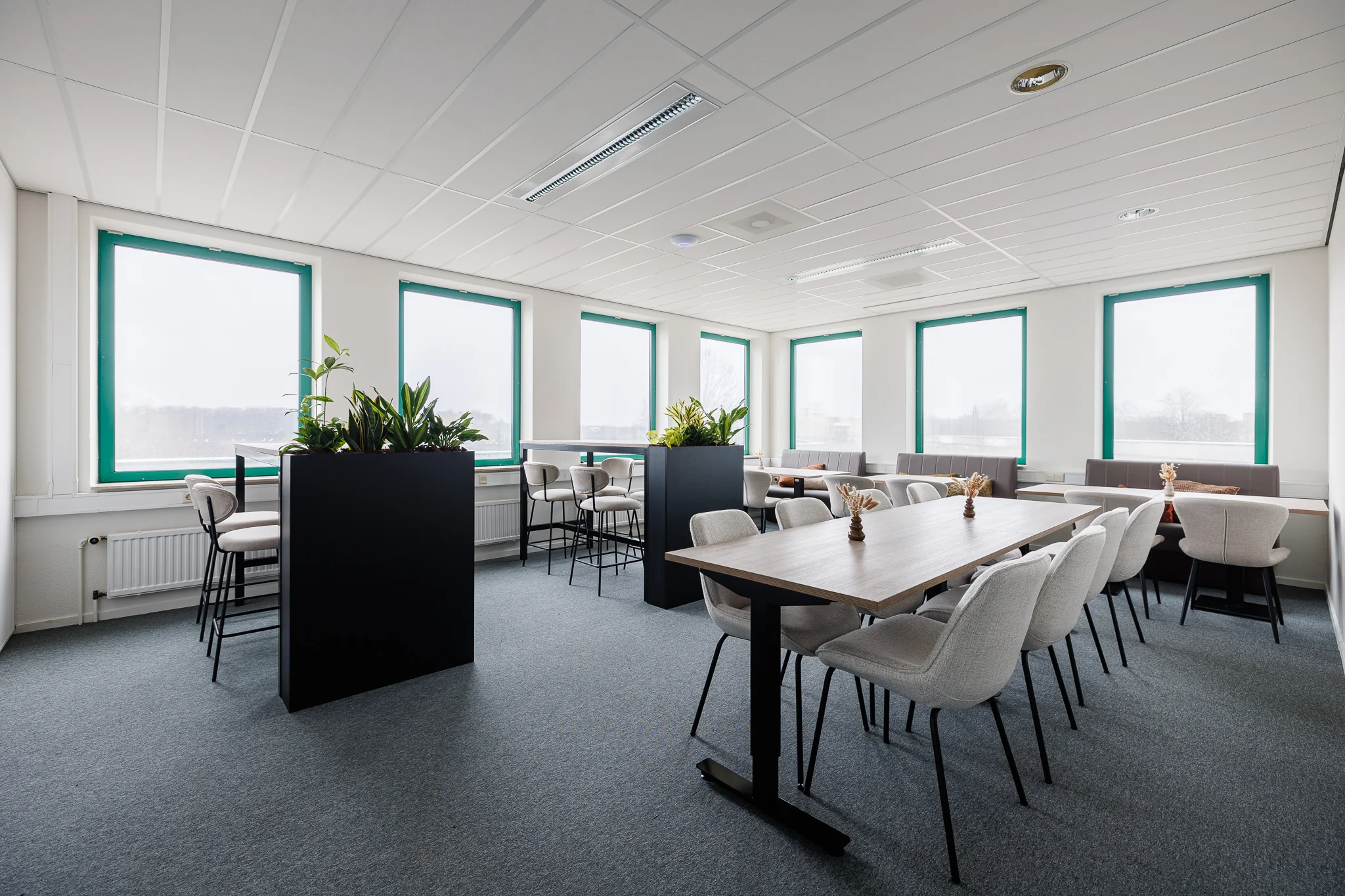 Een moderne kantoorruimte in Amersfoort met tafels, stoelen en planten.