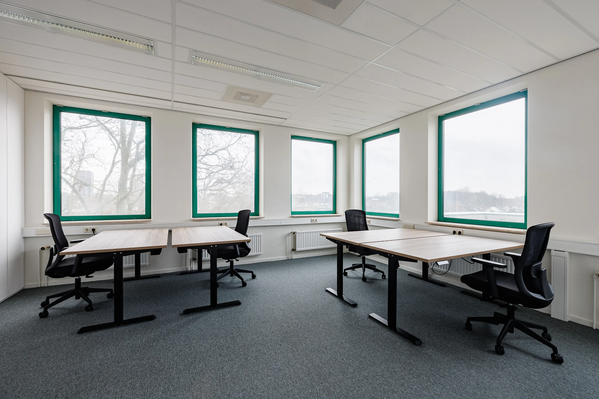 Kantoorruimte met vier bureaus en bureaustoelen bij grote ramen in Stadsring 201, Amersfoort.