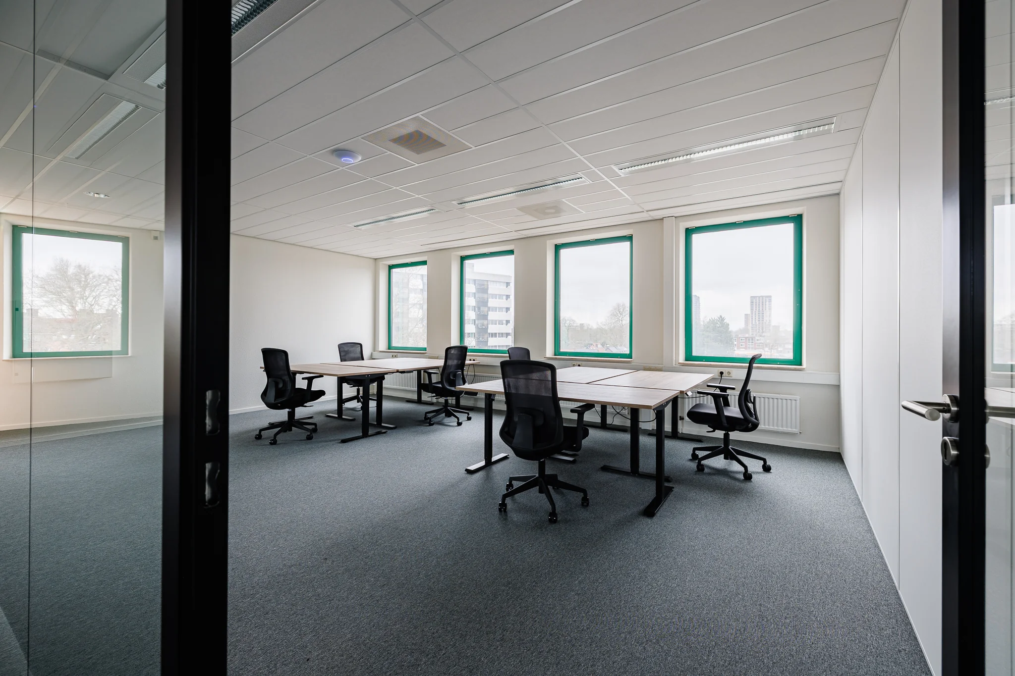 Licht kantoor met bureaus en stoelen bij grote ramen in Stadsring 201, Amersfoort.