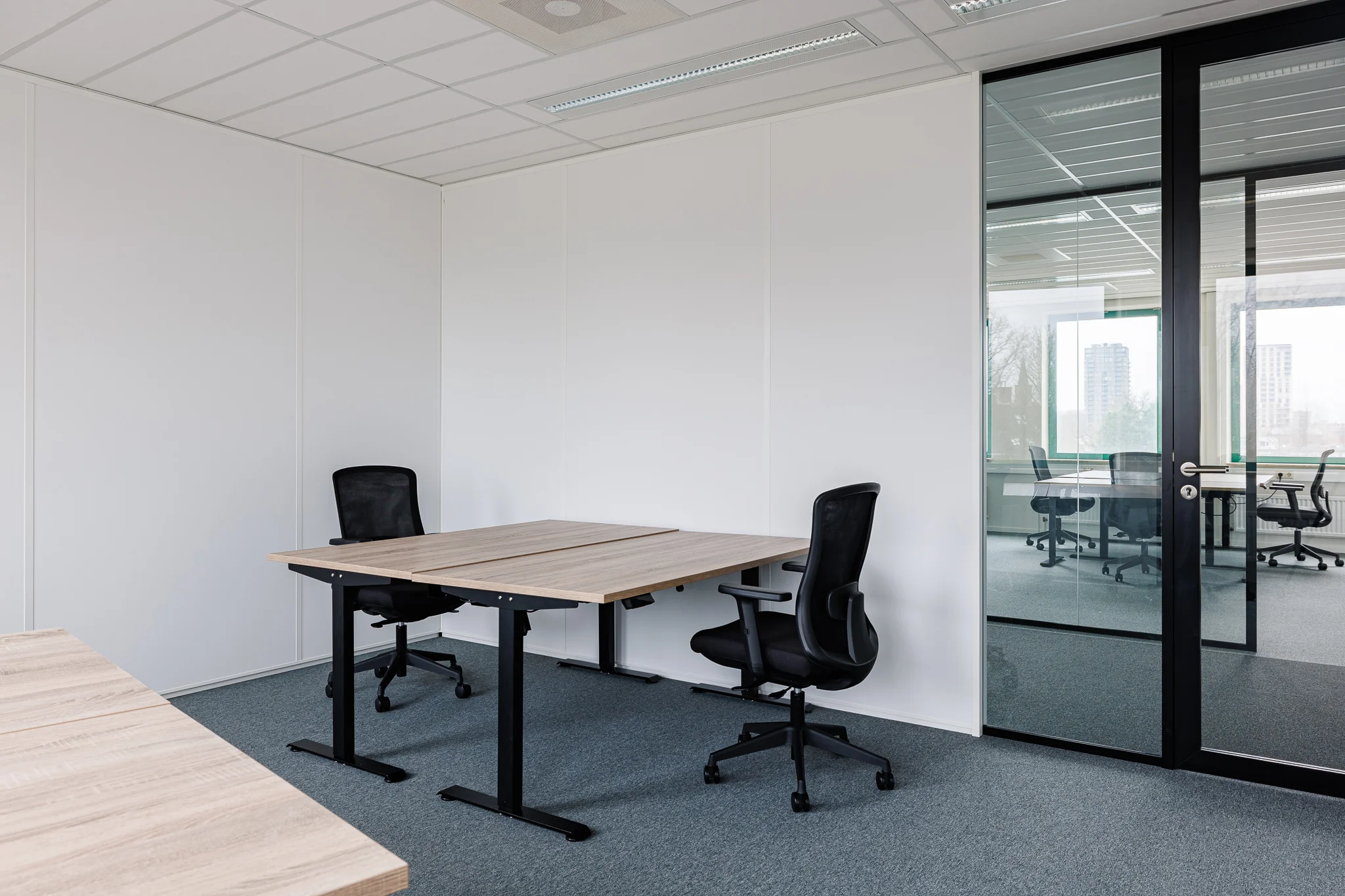Een moderne, minimalistische kantoorruimte met houten bureaus en ergonomische stoelen.
