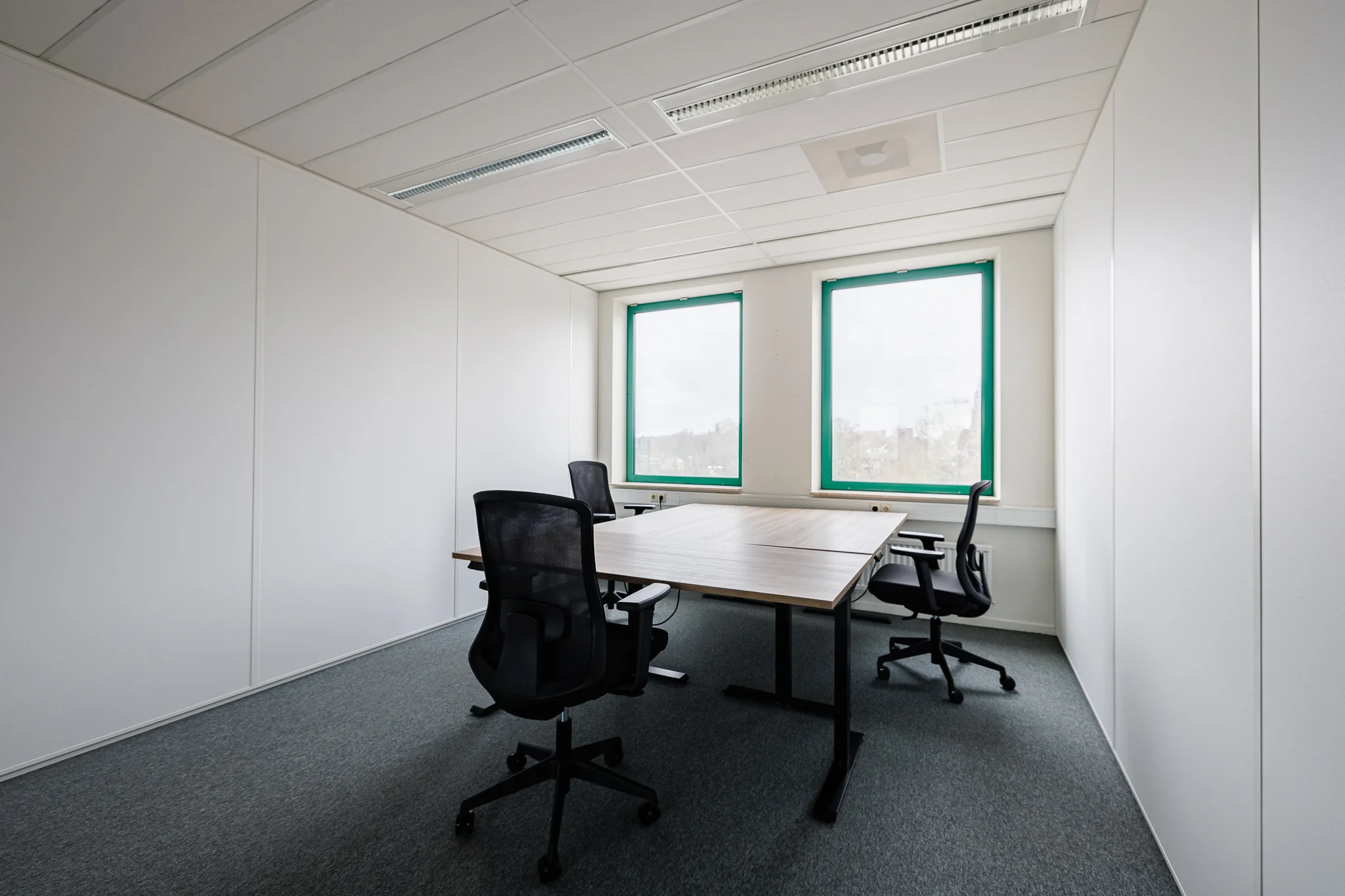 Een moderne, lege kantoorruimte met vier bureaustoelen en twee ramen, gelegen in Amersfoort.