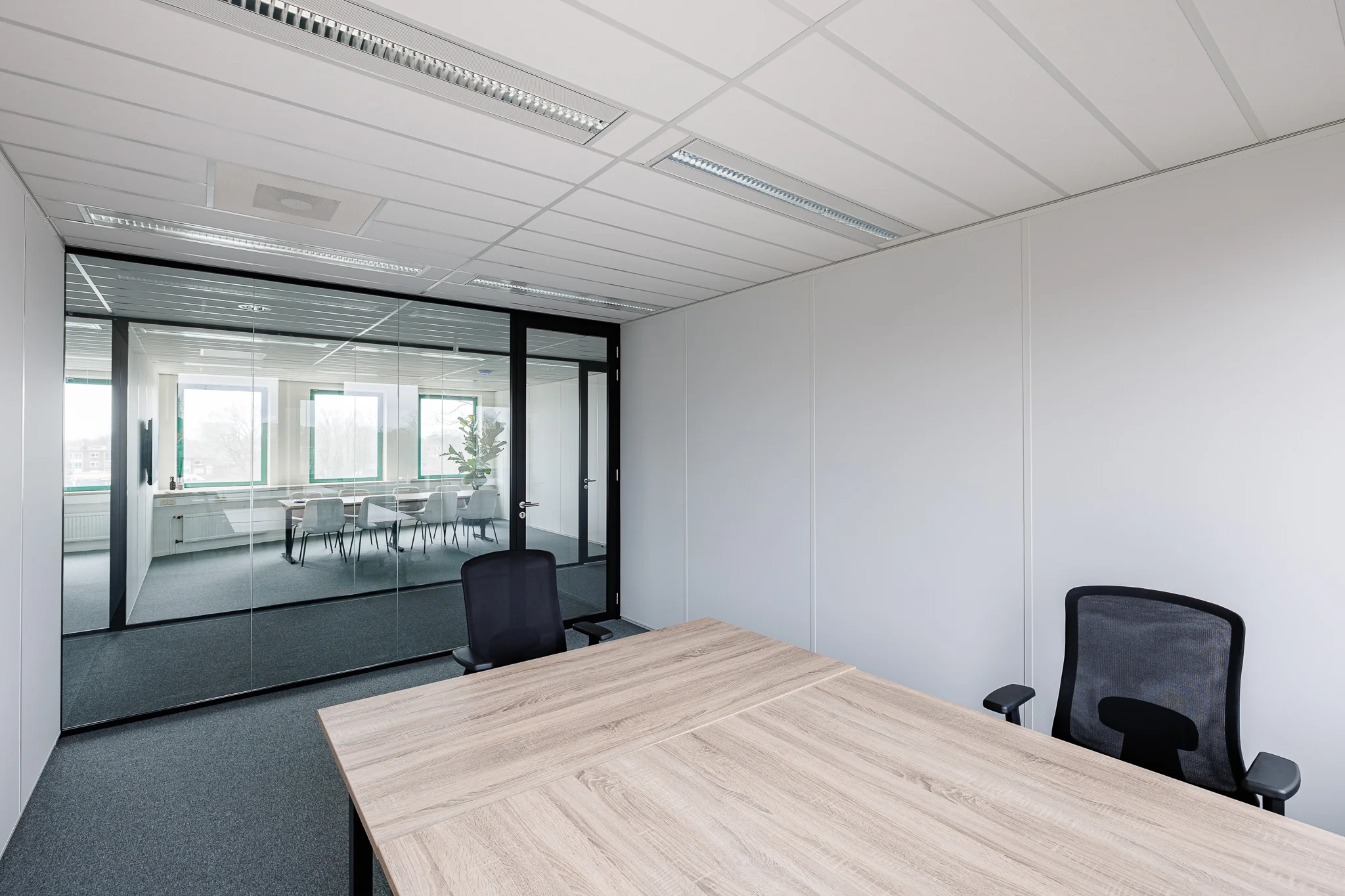 Een moderne vergaderruimte met een houten tafel en glazen wand in een kantoor in Amersfoort.