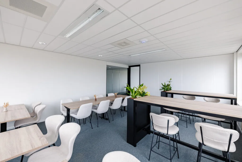 Een moderne vergaderruimte in Amersfoort met houten tafels, comfortabele stoelen en groene planten.