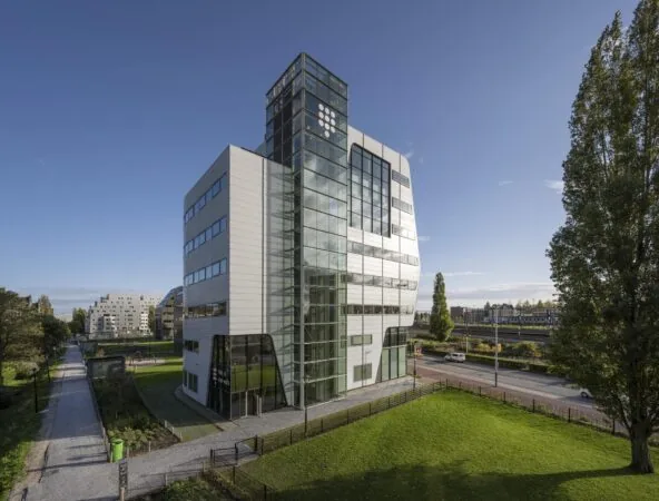 Modern kantoorgebouw aan het Rietlandpark in Amsterdam met glazen gevel en omliggend groen.