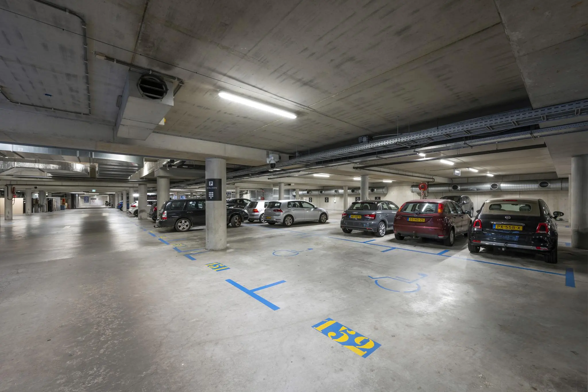 Ondergrondse parkeergarage in Rietlandpark met meerdere geparkeerde auto's en gemarkeerde parkeerplaatsen voor mindervaliden.