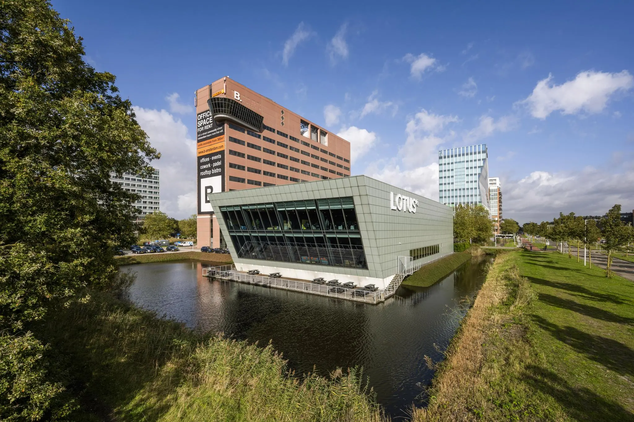 Modern kantoorgebouw Lotus aan de Johan Huizingalaan in Amsterdam, gelegen aan het water met omliggende hoogbouw en groenstroken.
