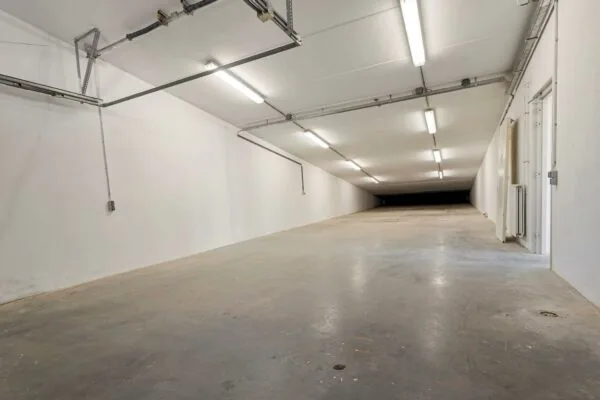 Lange, lege, wit verlichte parkeergarage of opslagruimte aan de Tijnmuiden.