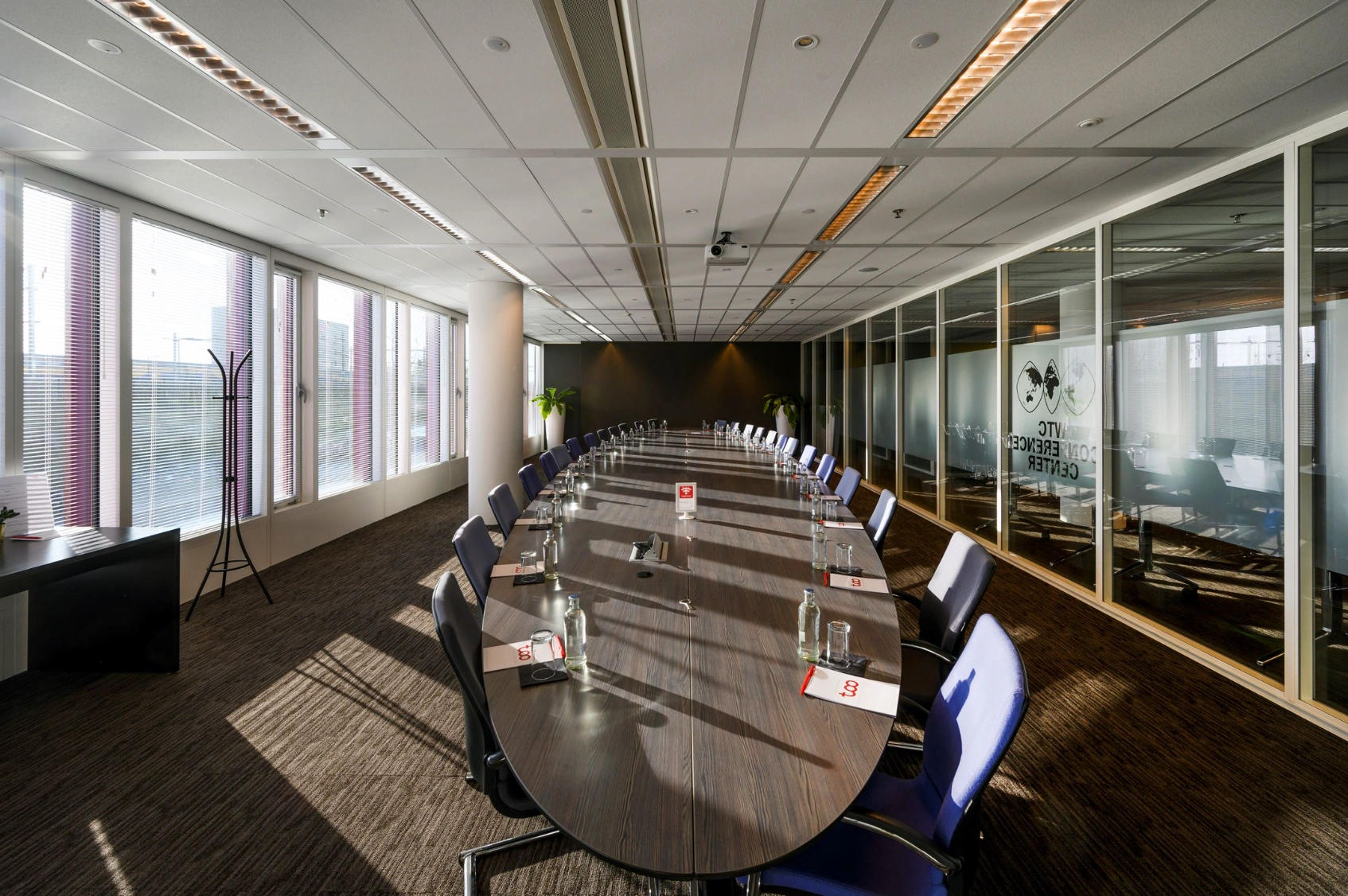 Vergaderruimte met een lange ovale tafel en voorbereidende materialen in het VTC Conference Center aan de P.J. Oudweg.