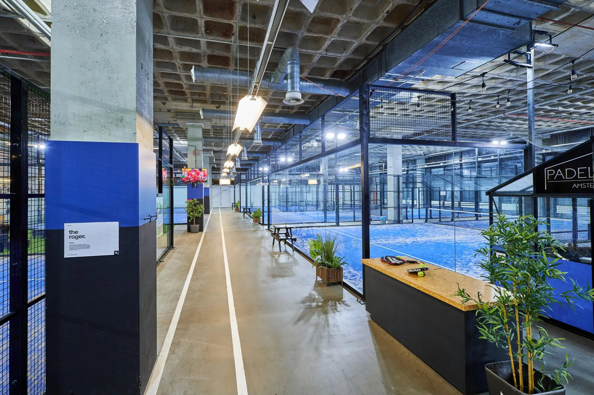 Indoor padelcentrum op het John M. Keynesplein in Amsterdam met meerdere blauwe padelbanen en een moderne industriële inrichting.