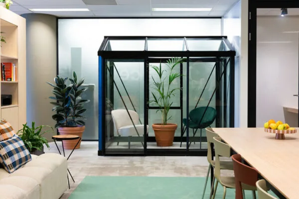 Moderne kantoorruimte aan de Johan Huizingalaan met glazen vergaderkas, planten, zitgedeelte en vergadertafel.