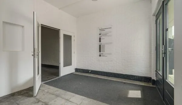 Entreehal van het bedrijfsverzamelgebouw aan de Mercuriusweg met witte muren, glazen deuren en een overzichtsbord met bedrijfsnamen.