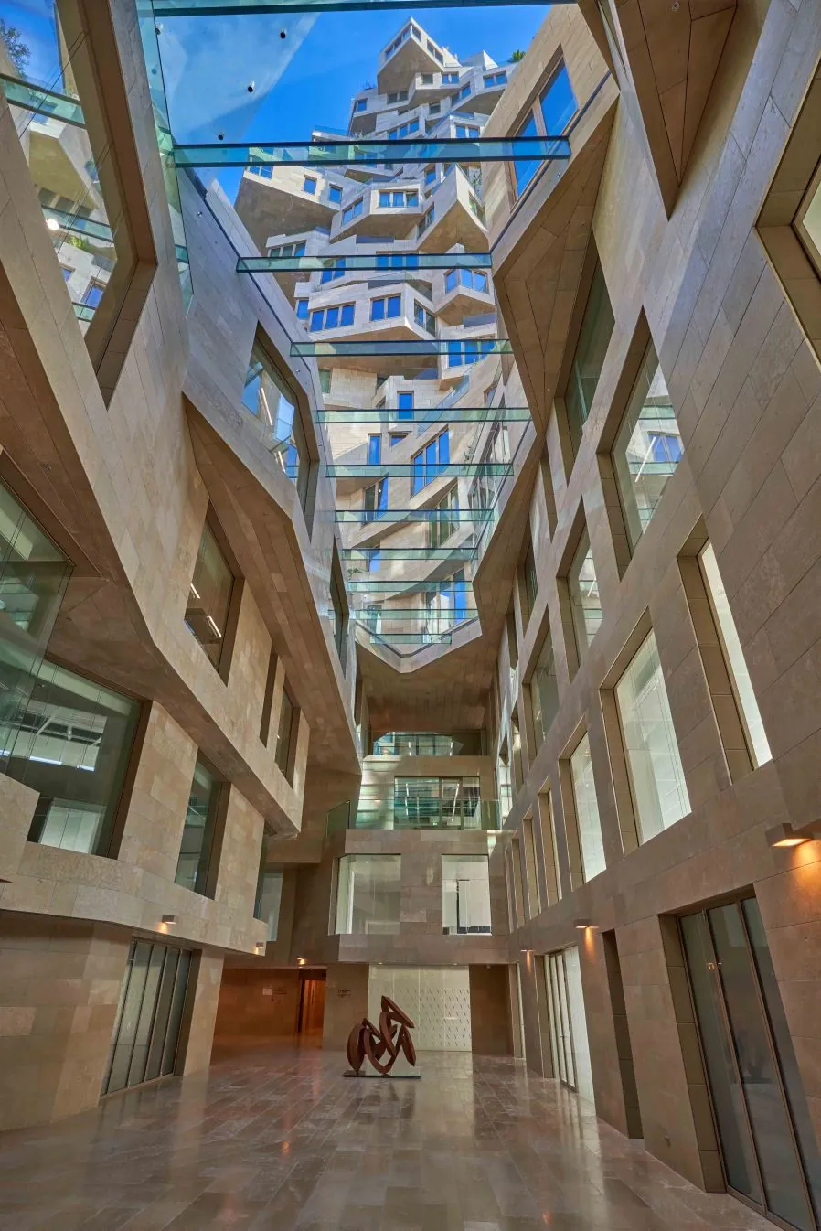 Atrium van het NACH-gebouw aan de Beethovenstraat met moderne architectuur, glazen plafonds en een sculptuur op de begane grond.