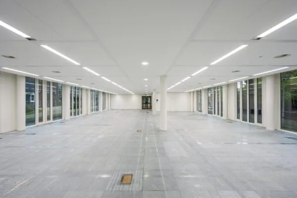 Leeg, modern kantoorpand aan de De Cuserstraat met grote ramen en systeemplafondverlichting.