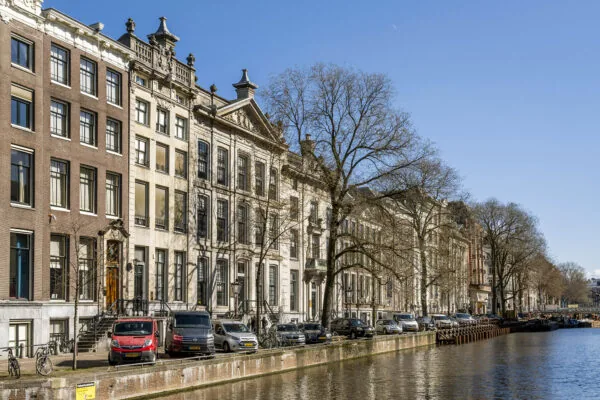 Rijtje monumentale herenhuizen langs de Herengracht in Amsterdam op een zonnige dag.