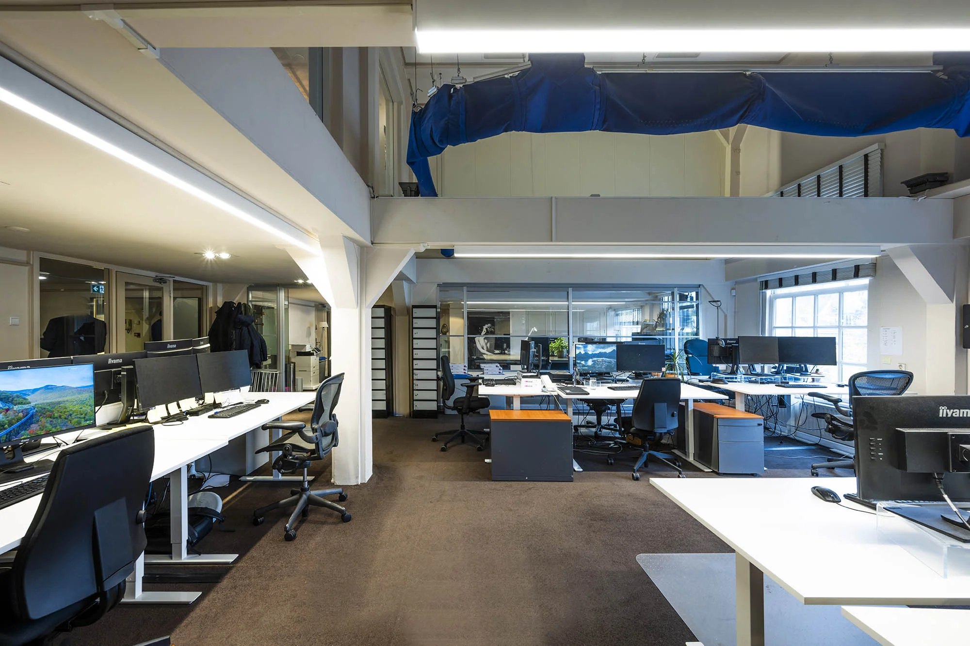 Modern kantoorpand aan de Herengracht met open werkplekken, bureaus en computerschermen.