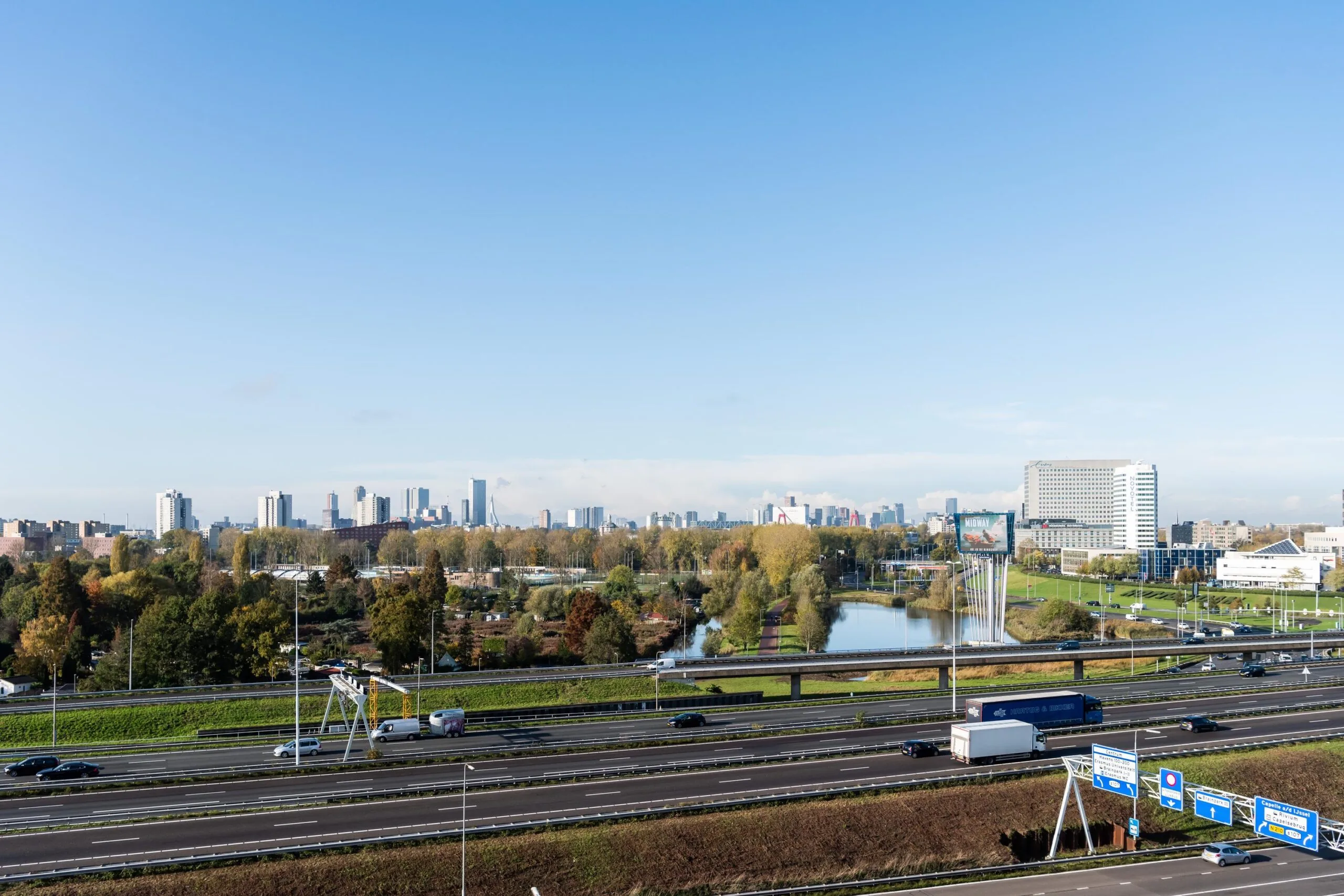 View of the Rivium Quadrant business district with highways, green areas, and the Rotterdam skyline in the background.