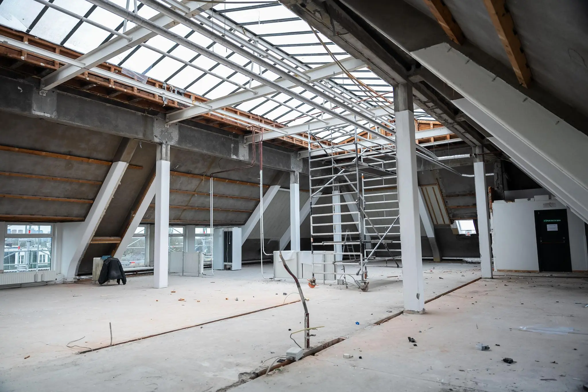 Ruime zolderverdieping op WG-Plein in verbouwing met steiger, schuine dakconstructie en grote dakramen.