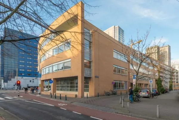 Hoekpand aan het Spui in Den Haag met oranje baksteen en afgeronde gevels, omringd door moderne hoogbouw.