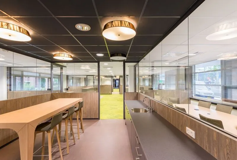 Moderne kantoorruimte aan het Spui met glazen wanden, houten meubilair en een open werk- en vergadergedeelte.
