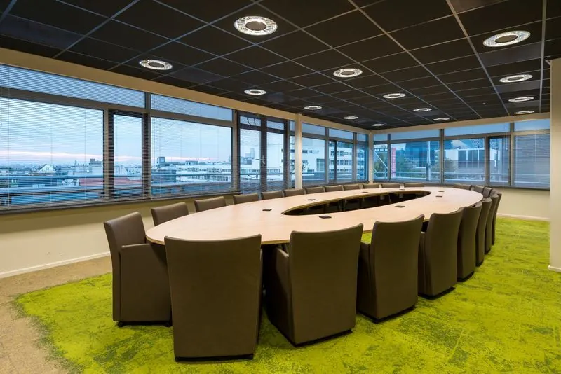 Vergaderruimte met ovale tafel, moderne stoelen en uitzicht op de stad vanaf de bovenverdieping van het gebouw aan het Spui.