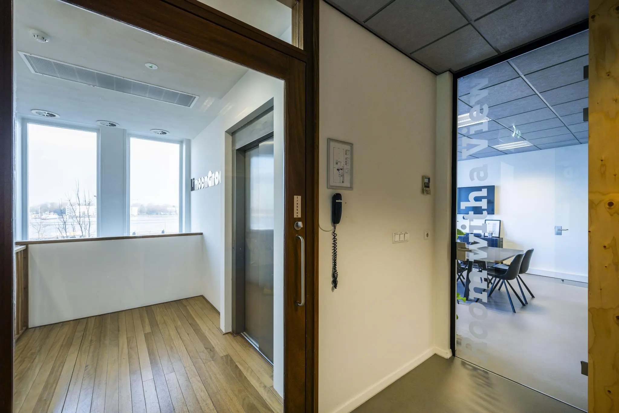 Binnenruimte met een glazen deur naar vergaderruimte “room with a view” en uitzicht op het IJ vanaf De Ruijterkade.