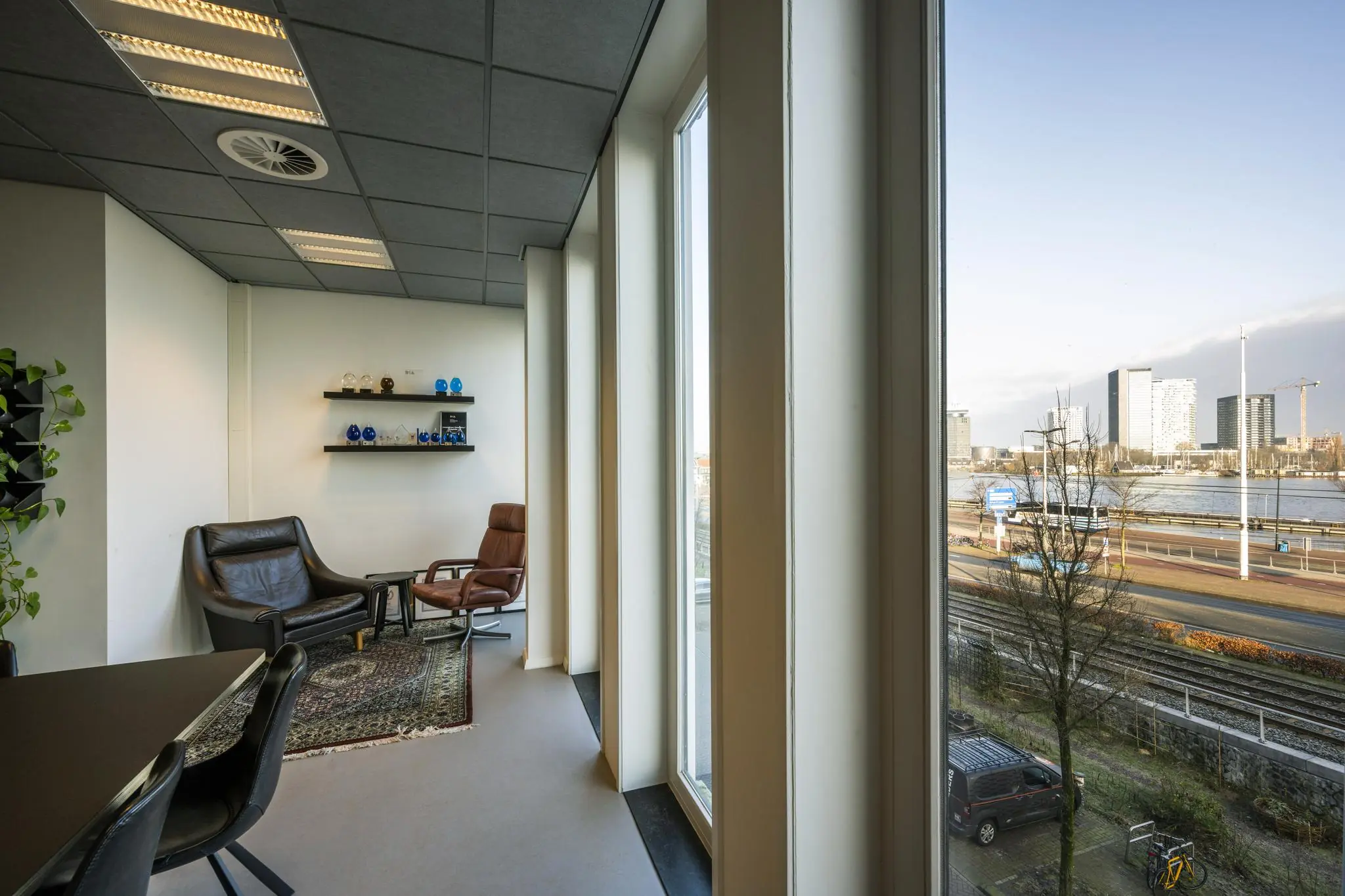 Zitruimte met leren stoelen en uitzicht op het IJ vanaf een kantoor aan de De Ruijterkade in Amsterdam.