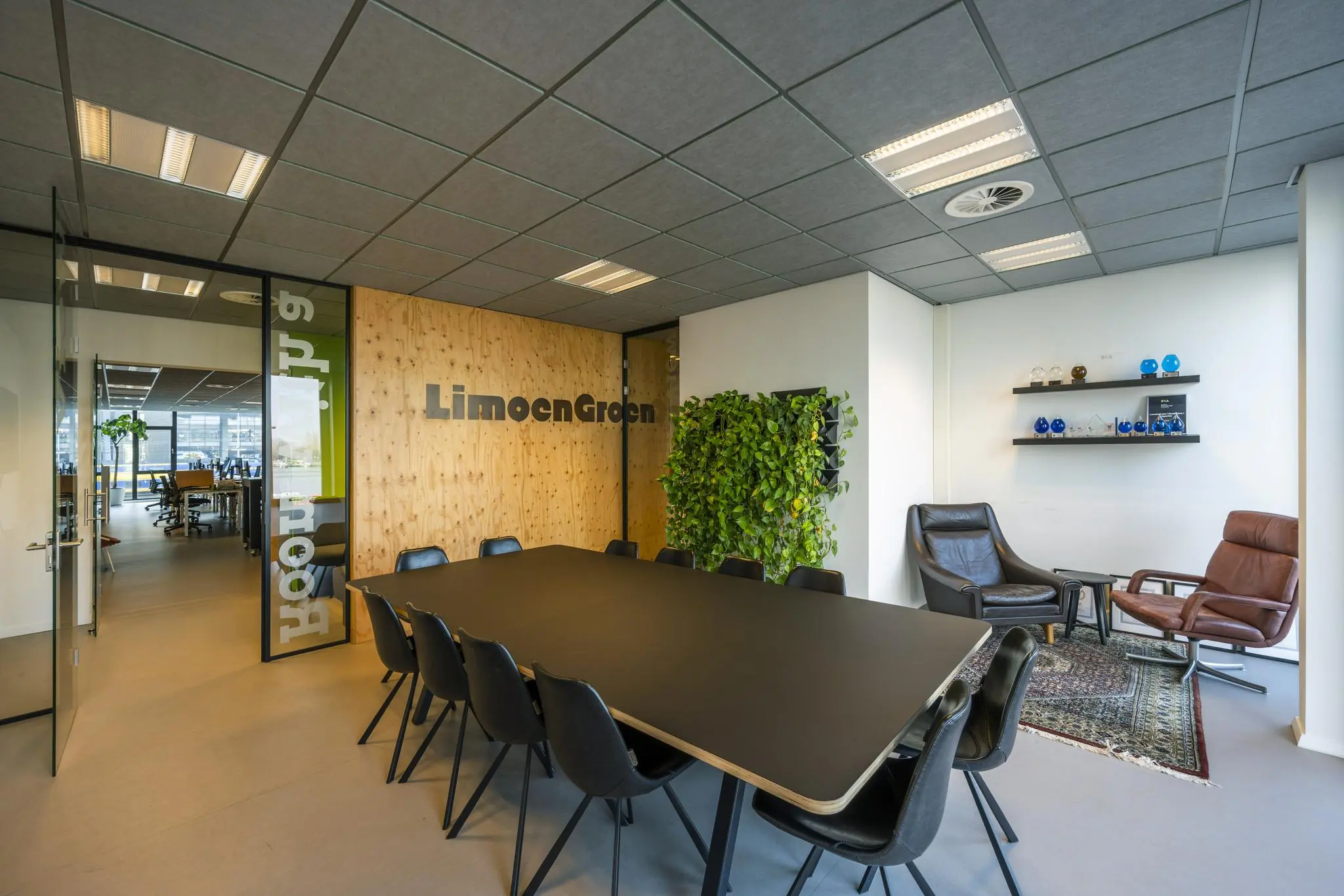 Vergaderruimte van LimoenGroen aan de De Ruijterkade met een grote tafel, moderne stoelen, plantenwand en zithoek.