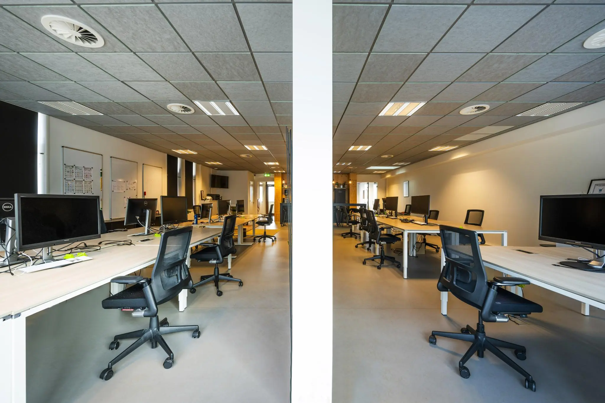 Modern, open kantoorpand aan de De Ruijterkade met meerdere werkplekken en bureaustoelen in een symmetrische opstelling.