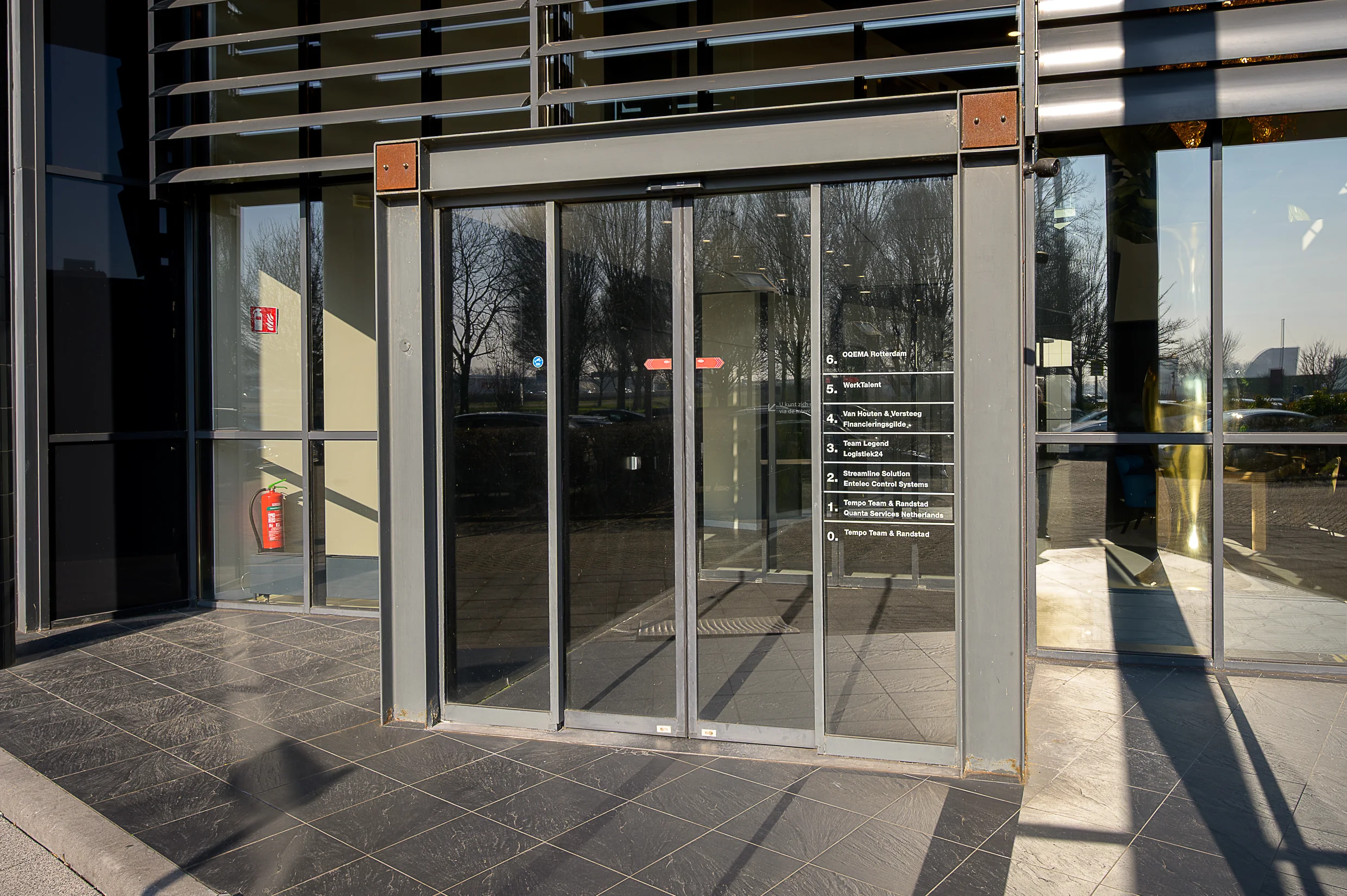 Glass entrance doors of the Rivium Quadrant office building displaying company names and floor numbers.