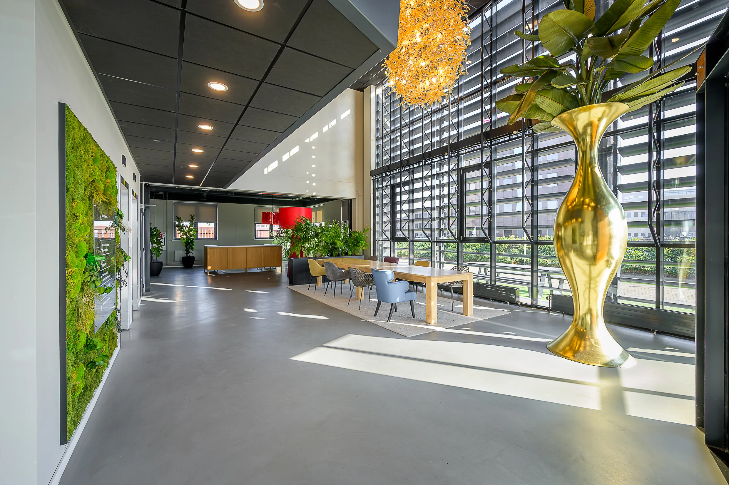 Modern office lobby at Rivium Quadrant featuring a large gold vase, indoor plants, and a seating area with natural light.
