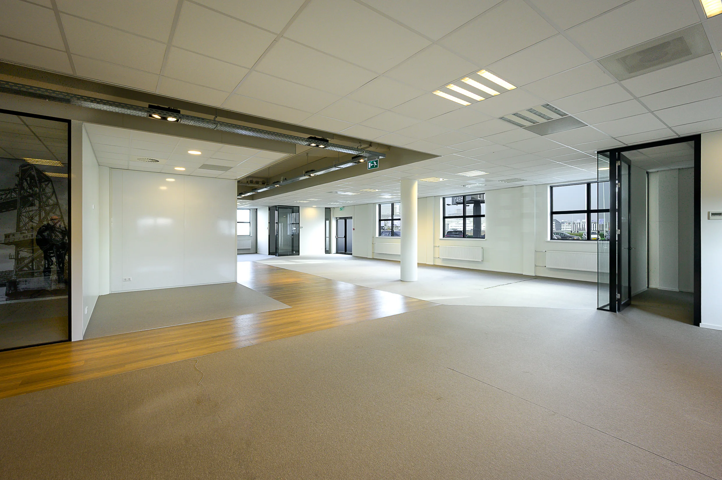 Modern empty office space in Rivium Quadrant with mixed flooring, large windows, and glass doors.