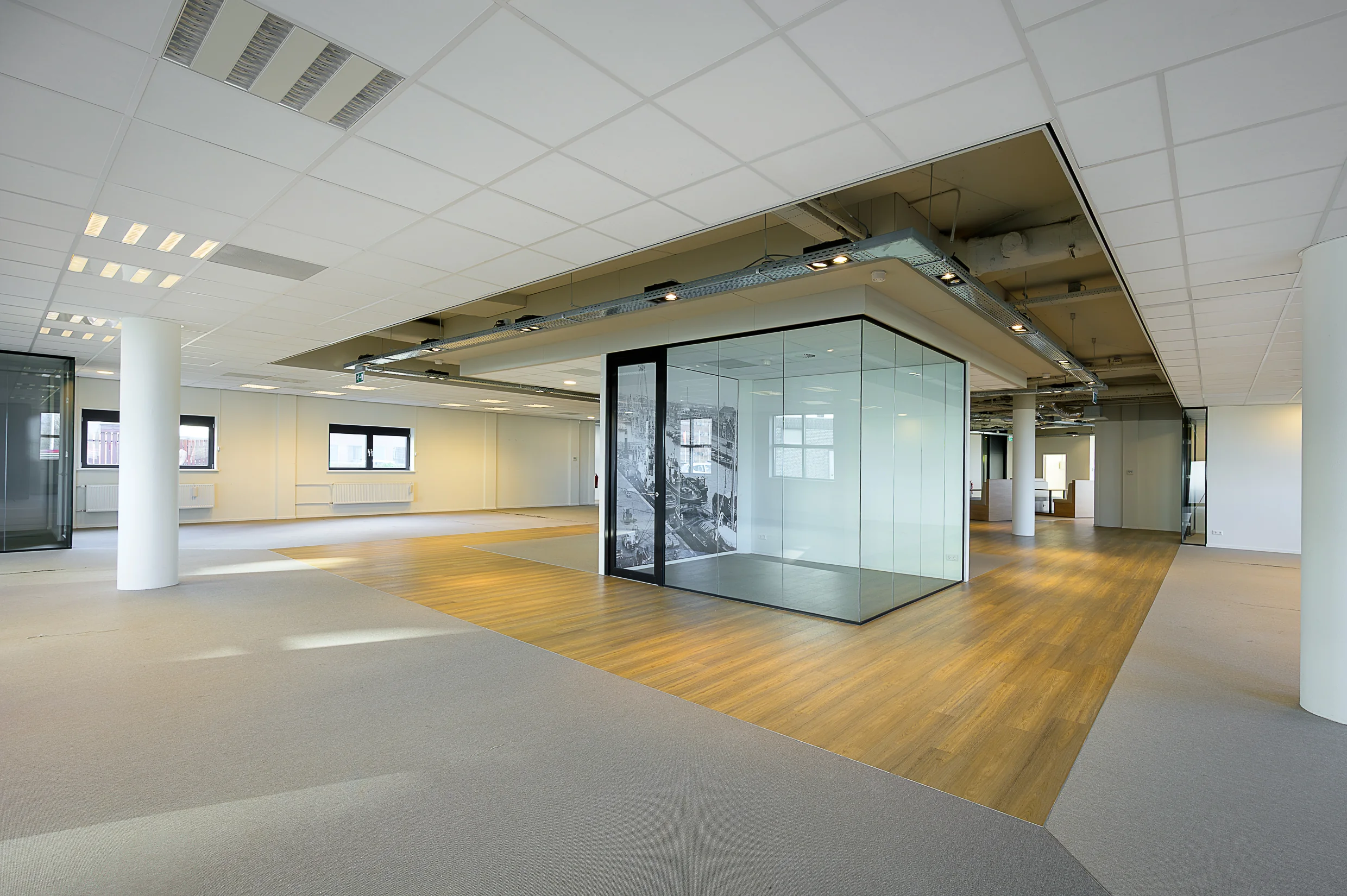 Modern, unfurnished office space at Rivium Quadrant with glass-walled meeting room and mixed flooring.