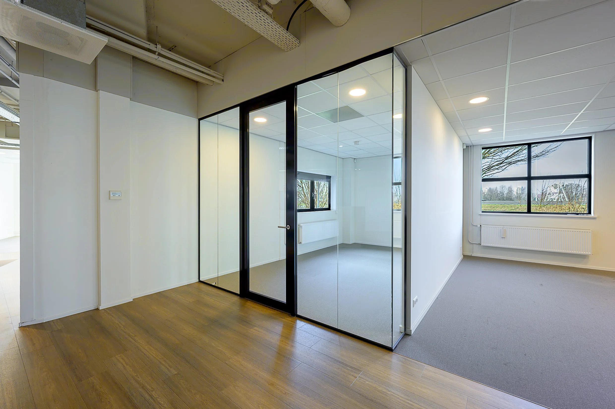 Modern office space at Rivium Quadrant with glass-walled meeting room and large windows.