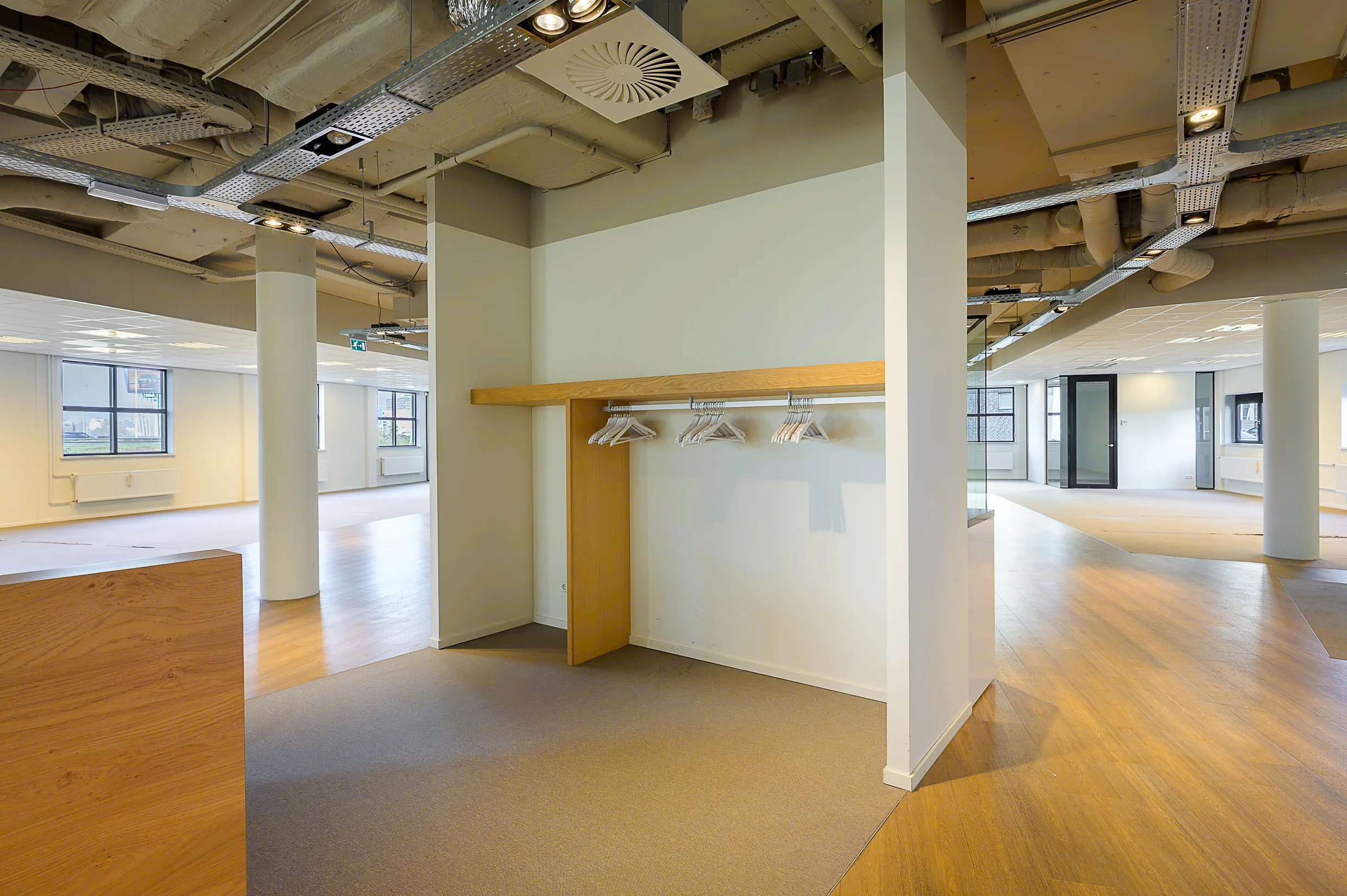 Modern empty office space at Rivium Quadrant with a built-in coat rack and exposed ceiling elements.