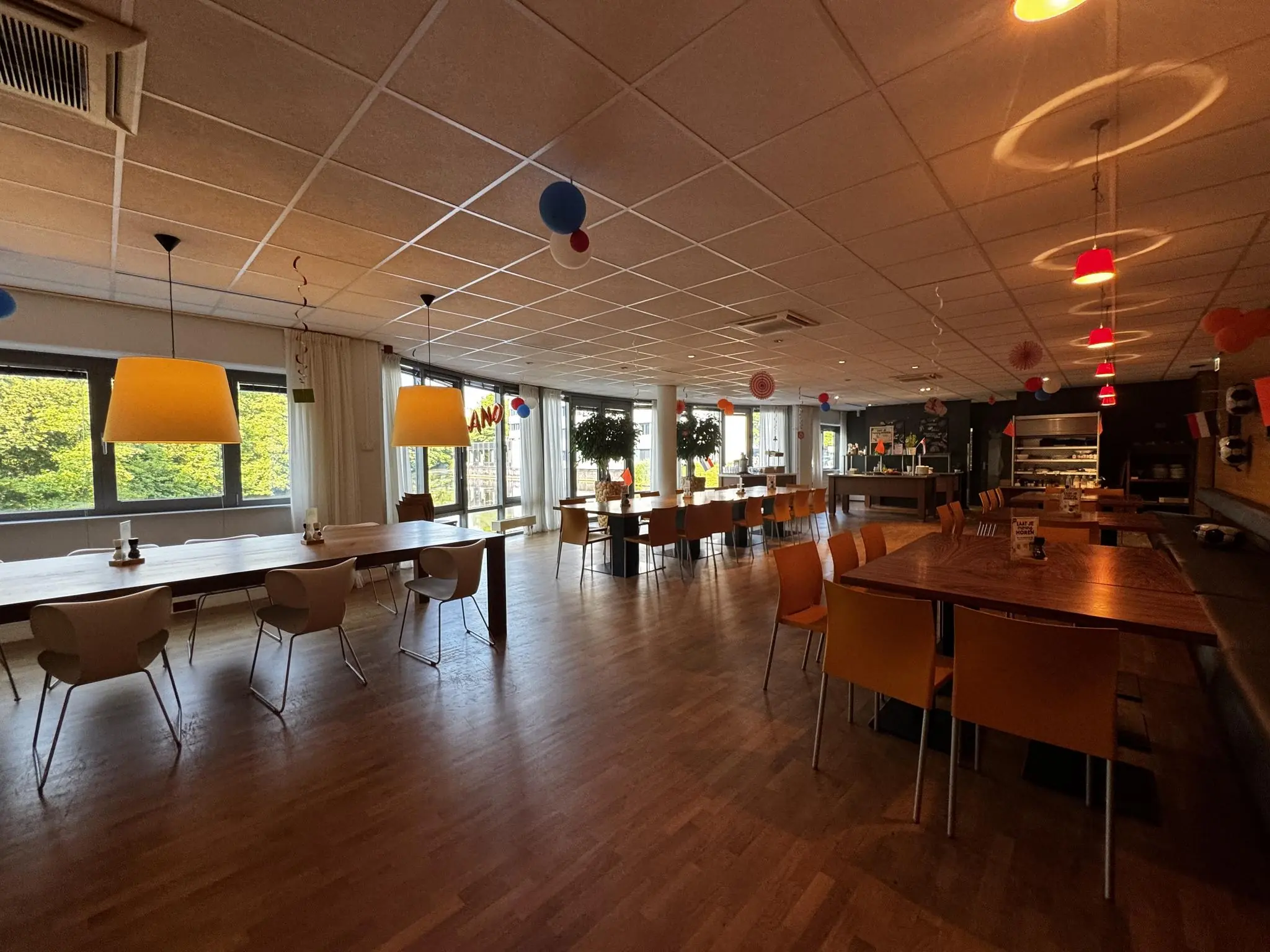 Moderne bedrijfskantine aan de Softwareweg met houten vloer, kleurrijke stoelen en feestelijke versiering.