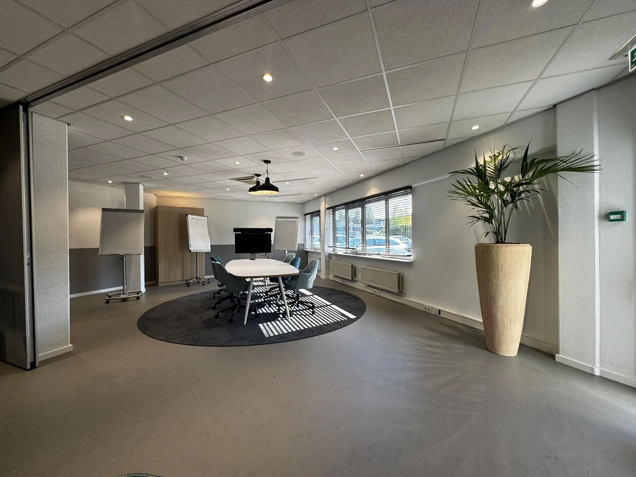 Moderne vergaderruimte aan de Softwareweg met ovale tafel, stoelen, flip-overs, groot scherm en veel daglicht.