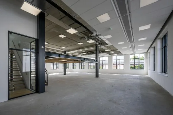 Moderne, lege kantoorruimte aan de Nicolaas Tetterodestraat met grote ramen, betonnen vloer en een metalen tussenverdieping.